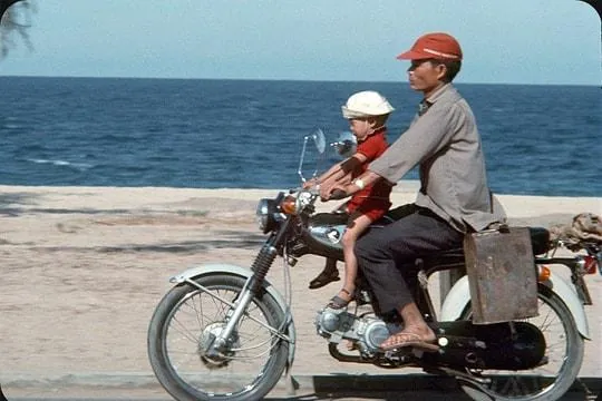 Pai e filho de Honda 50 junto à praia